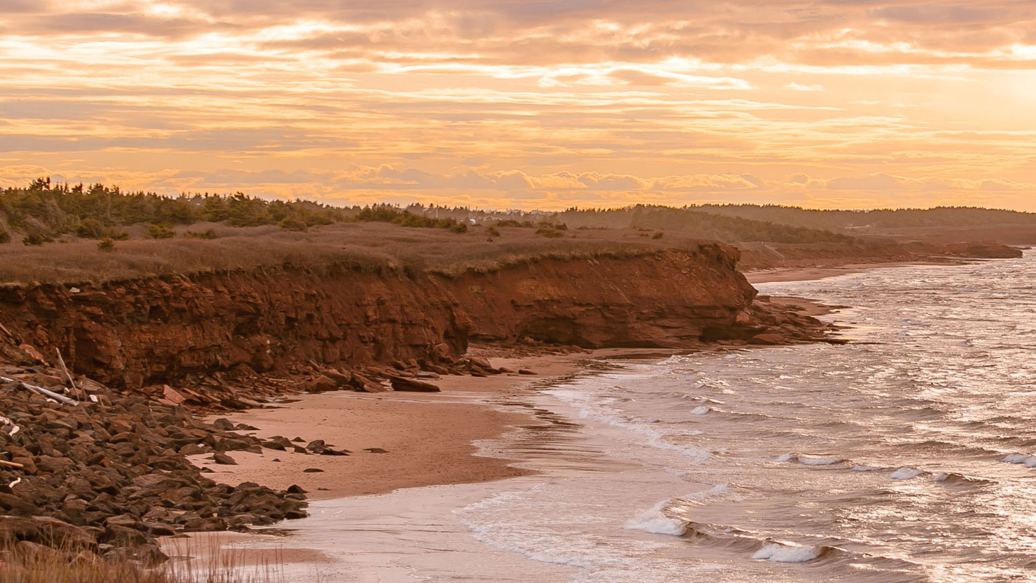 image of red cliffs and the ocean during sunset on Prince Edward Island